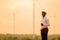 African engineer windmills wearing white hard hat and using tablet with   wind turbine on silhouette sunset