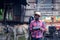 African farmer man with retro radio broadcast receiver on shoulder stands happy smiling outdoor on old cow stall background