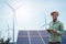 African farmer standing and holding digital tablet on corn farm with solar cell and wind turbine in background.Concept of green