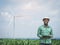 African farmer standing and holding digital tablet on corn farm with  wind turbine in background.Concept of green power
