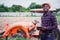 African farmer is using a tablet on the background of working tractor with a cultivator in the field.Agriculture or innovate