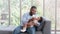 African father Sitting on sofa, holding and feeding newborn baby from bottle milk in living room. Authentic lifestyle candid real