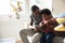 African father teaching son how to play guitar