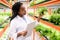 African female biologist with document standing by shelves with green seedlings