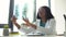 African female doctor with glasses looking at x-ray of lungs while sitting at table in modern clinic