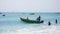 African fishermen launching small wooden skiff from a tropical beach on Cape Verde Islands