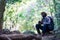 African freedom man traveler holding camera with backpack sitting in the green natural forest