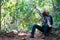 African freedom man traveler holding camera with backpack standing in the green natural forest