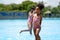 African girl standing and playing in swimming water pool at amusement park.  Concept kid are expressing pure joy and excitement