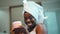 African girl with a towel on her head sticks skin care cream in her hands