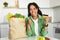 African lady with grocery bag holding credit card in kitchen