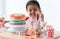 African little kid girl in cute dress, surprised on birthday party with beautiful rainbow cake decorated with sugar candies, color