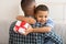 African Little Son Hugging Dad Receiving Birthday Gift At Home