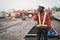 African machine engineer technician talking with walkie talkie and wearing a helmet, groves and safety vest is using a wrench to