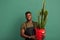 African male florist in apron standing with a big cactus planted in red bucket