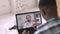 African man in casual clothes, with thermometer in hands, having video call with doctor on laptop