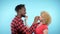 African man Caucasian woman eating black and white marshmallows. blue background