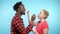 African man Caucasian woman eating chocolate and creamy yogurt. blue background