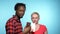 African man , Caucasian woman to eat black and white chocolate. blue background