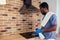 African man cleaning cooktop cooker hood at home ,Brick wall background