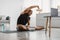 African Man Doing Sitting Side-Bend Stretch At Laptop At Home