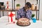 African man with dreadlocks celebrating birthday holding big chocolate cake thinking looking tired and bored with depression