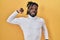 African man with dreadlocks wearing turtleneck sweater over yellow background stretching back, tired and relaxed, sleepy and