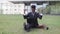 African man keeping arms raised and fists clenched and expressing joy, sitting with laptop outside