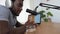 African man recording a podcast using microphone and laptop from home studio