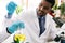 African man scientist researcher use a lab dropper to drip a substance into a conical flask for analysis of liquids.