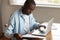 African man sitting at table paying household bills using laptop