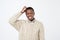 african man in sweater thinking scratching head on white background. How is it supposed to be done concept