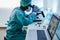 African medical worker in hazmat suit working with microscope inside laboratory hospital during coronavirus outbreak - Focus on