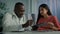 African middle-aged doctor man physician help young woman patient check medical insurance electronic health test results