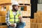 African middle aged engineer worker beard man wear safety hat, eating burger, coffee in lunch break at warehouse. Foreman relaxing