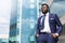 African millenial man in suit standing near the office building filled with gratitude with copy space