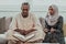 African Muslim couple at home in Ramadan reading Quran holly Islam book.