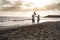 African parents and little son having fun on the beach at sunset - Family people and love concept - Focus on silhouette bodies