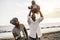 African parents and little son having fun with wood airplane on the beach - Focus on mother face