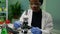 African researcher taking green leaf sample from petri dish putting under microscope