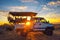 African safari vehicle stops in the Kalahari desert for dramatic sunset