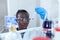 African scientist looking pensive at test tube with blue liquid