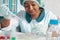 African scientist, technical assistant or medical technician in white coat, protective hat and gloves optimizes PCR testing for