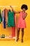 African Shopaholic Lady Shopping Holding Hanger With Dress, Yellow Background