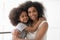 African single mother and child daughter embrace looking at camera