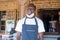 An african small business owner wearing a face mask in front of his store and smiling