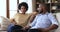 African spouses having conversation seated on sofa indoors