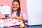 african tailor with afro dreadlocks pigtails sews clothes on sewing machine at tailor office pink wall background