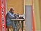 African Tailor Sitting at Sewing Machine Reading Newspaper