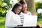 African teens playing on laptop in park.